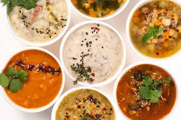 Various delicious and healthy soups in bowls on white background, top view. Vegetable soups, cream soups.
