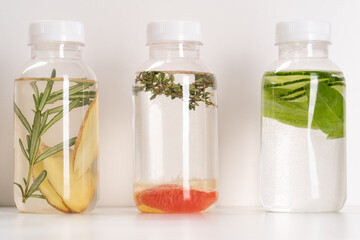 Detox Infused Water with Grapefruit, Ginger, Cucumber, Rosemary, Herbs and Mint in Bottles on a White Background. Healthy Beverage. Food diet concept. Vegetarian.