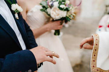 The priest blesses hands with the wedding rings of the bride and groom in the church.