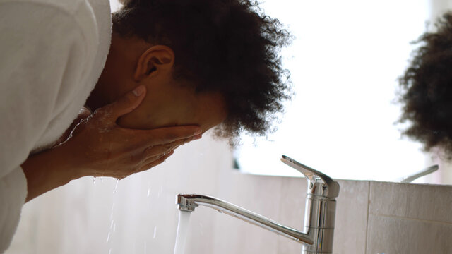 Close Up Of African Man Washing Face In Bathroom Sink