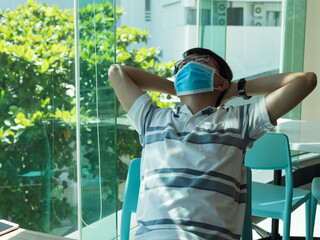 Asian man wearing medical face mask to prevent from covid 19 in room , sitting with tired posture.