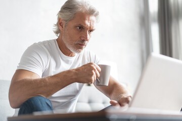 Fototapeta premium Middle-aged man working from home-office on laptop