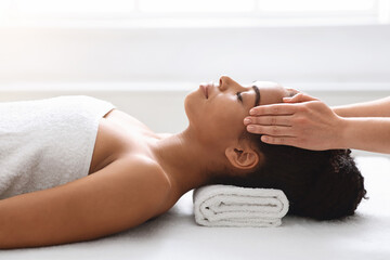 Obraz na płótnie Canvas Peaceful african american woman getting healing head massage at spa