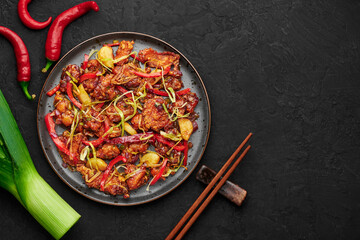 Kkanpunggi or Korean Spicy Garlic Fried Chicken on black plate on dark slate table top. Kan Pung Gi is korean and chinese cuisine dish. Typical asian food and meal. Top view. Copy space