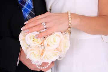 bride and groom hands with brides hand sat atop flowers