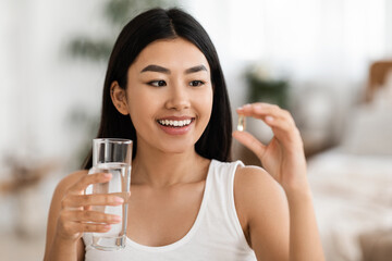 Happy Asian Woman Taking Pill In Morning