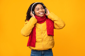 Fototapeta premium Black Woman Listening Music In Earphones On Yellow Studio Background
