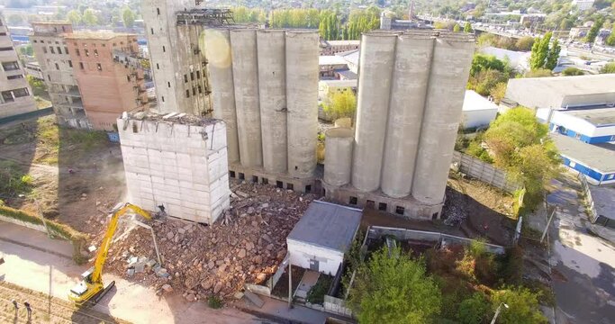 Kharkiv, Ukraine - 18 october 2020: a large excavator destroys an abandoned concrete grain elevator building that was left after the demolition. Aerial view