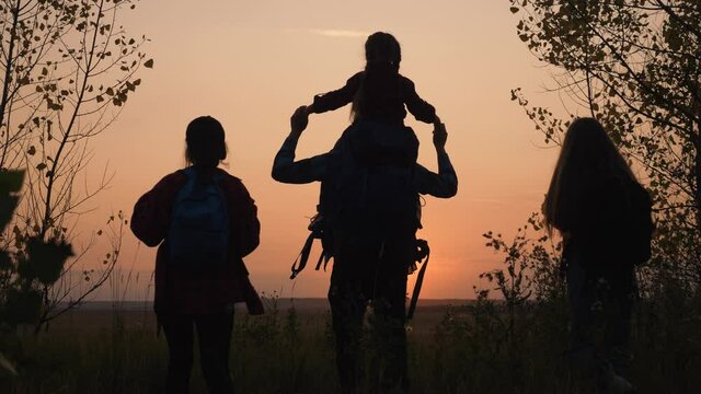 Tourists teamwork. Happy family in the park. Hiker hiking climbing. Happy family of tourists with backpacks going hiking. Silhouette group of tourists in the park at sunset.Teamwork on Hiking.