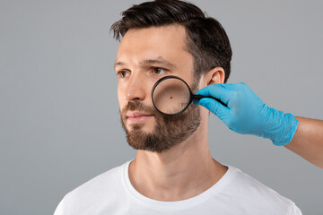 Doctor Hand Checking Face Skin Of Man With Dermatoscope