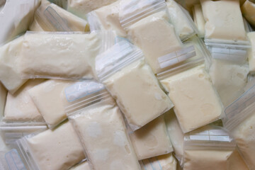 frozen breast milk in plastic bags. melting frozen mother milk background and texture.