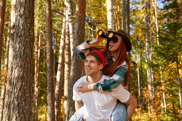 happy caucasian couple having fun during hike, travel in the forest, on mountains. carefree travellers enjoy the nature, use binoculars, smile