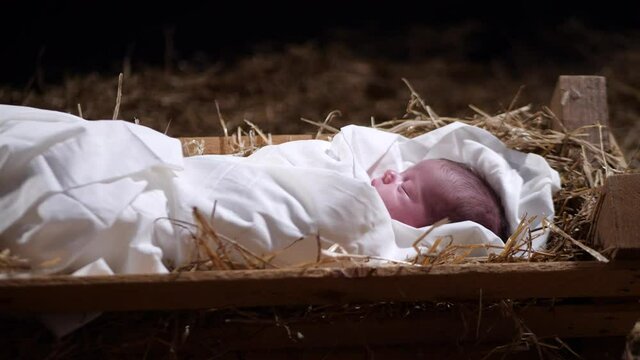 4K Dolly: Baby Jesus sleeping in a Manger with straw and Hay. Christmas Scene for the Nativity in a stable.