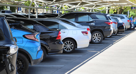 Closeup of rear, back side of blue car with  other cars parking in parking lot in bright sunny day. 