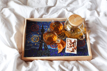 Tea and candied fruit on a tray in bed.