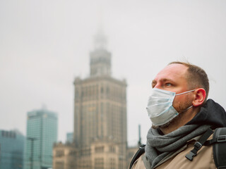 adult european man wearing a mask outdoor near Palace of Culture and Science in Warsaw city in...