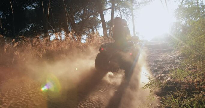 Two girl friends riding quad bike up hill in forest