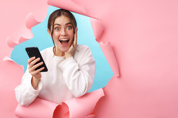 Caucasian young woman expressing surprise while holding cellphone