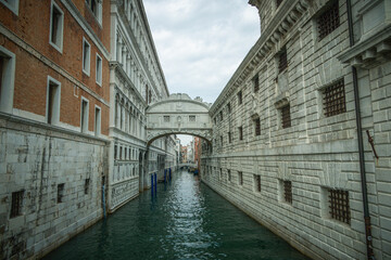 Naklejka premium View of one of the beautiful canals of Venezia from a bridge, during a cloudy day of high tide. World famous touristic destination, magic city built on water.