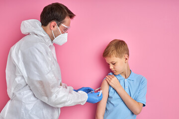 male doctor holding a syringe with needle and giving a vaccination at patient arm, isolated on pink background