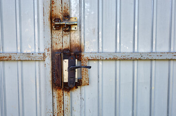 Iron rusty fence with a lock. White corrugated metal or zinc texture surface or galvanize steel in the vertical line background