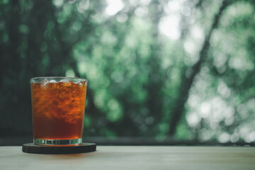 Homemade iced tea in small glass on wood table.