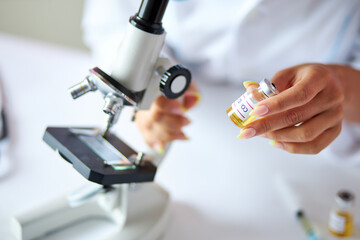 unrecognizable female scientist hold science or medical research, she is holding chemical liquid in laboratory background