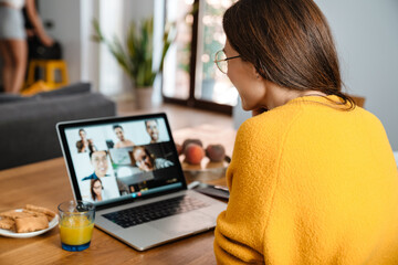 Happy woman smiling and having video call on laptop in apartment