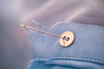 Needle with blue thread sewing button.