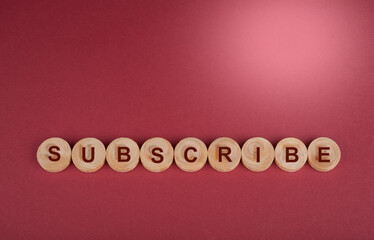 Subscribe sign on wooden wheels and red background