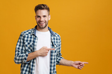 Joyful handsome unshaven guy smiling and pointing fingers aside