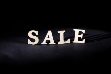 Obraz premium Word sale from wooden letters on a black background. Discounts and sales concept