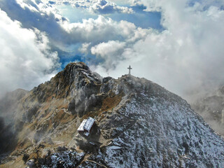 An aerial panorama of the peak of Mount Resegone next to Lecco, surrounded by clouds