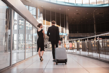 Fototapeta premium Woman and man carrying their suitcase through the airport