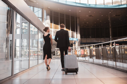Woman and man carrying their suitcase through the airport