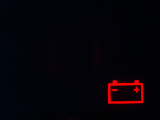 Red battery icon on a black background. Car battery discharge concept, copy space for text
