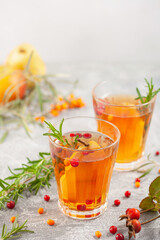 Winter or autumn hot healing tea with pear, orange, lingonberries, sea buckthorn and spices in glass cup.