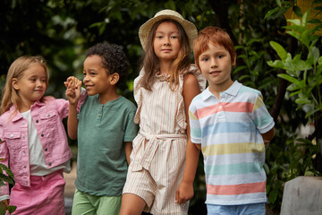 portrait of multi-ethnic children keen on nature, spending time in garden or hothouse, greenhouse. harvest, plants and living beings creatures around