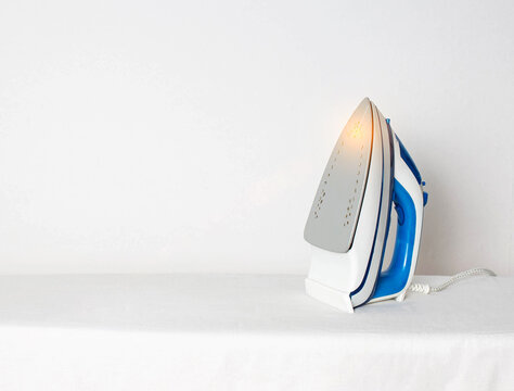 A modern iron with an aluminum sole for smoothing the folds of clothes. Hot and dangerous iron soleplate concept, fire hazard, copy space for text