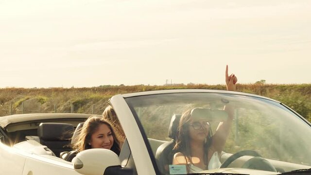 Slow motion shot of young women traveling in cabriolet and singing