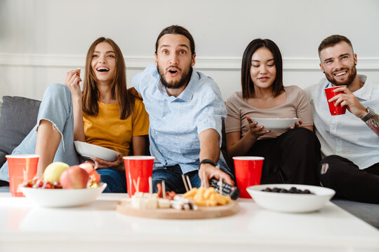 Image of friends drinking beverage and eating appetizer while watching tv