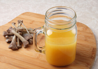 freshly made chicken bone broth in a mug with bones nearby