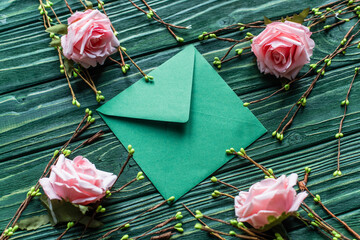 wooden green background with blossoming branches, roses and envelope