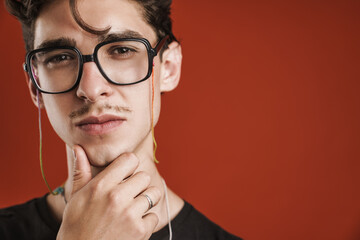 Pensive young hipster man standing isolated