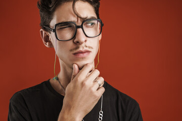 Pensive young hipster man standing isolated