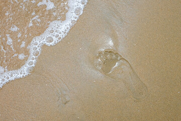 single footprint in the sand washed by wave