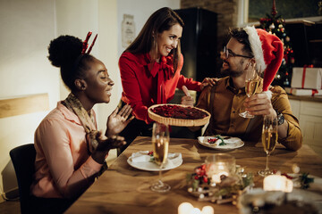 Happy woman serving cranberry pie for dessert while celebrating Christmas with friends at home.