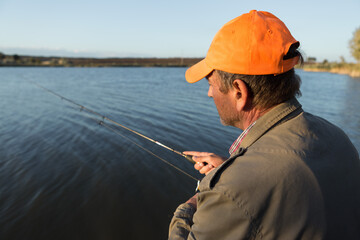 Fishing rod wheel closeup, man fishing with a beautiful sunset.