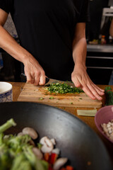 hands cutting vegetables and cooking asian food.