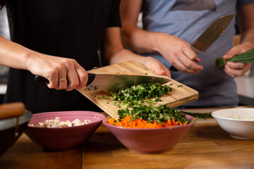 Hands chopping and preparing vegetables.

